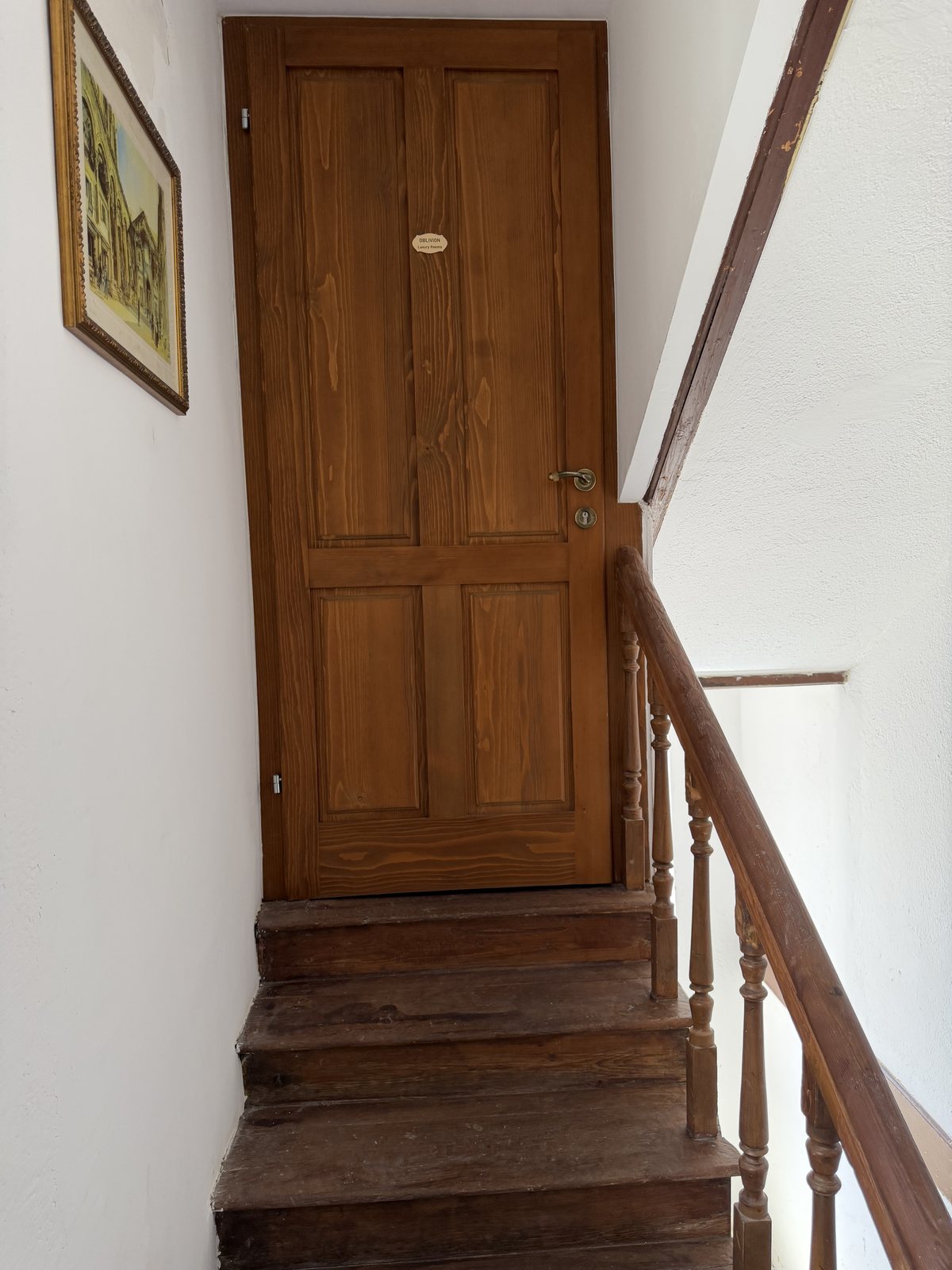 Wooden door at the top floor with Oblivion Luxury Rooms plate